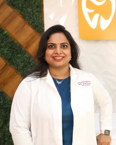Dr. Revathi Indukuri in a white coat at the reception of Elite Dental Clinic, Kondapur